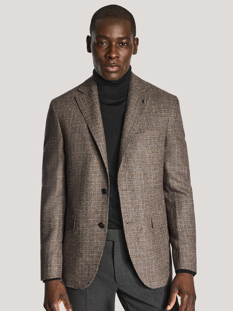 Brown and navy check blazer with notch lapels and two button closure worn over black turtleneck.