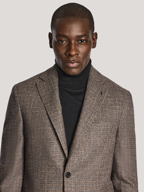 Man wearing brown and navy check blazer with notch lapels over a black turtleneck.