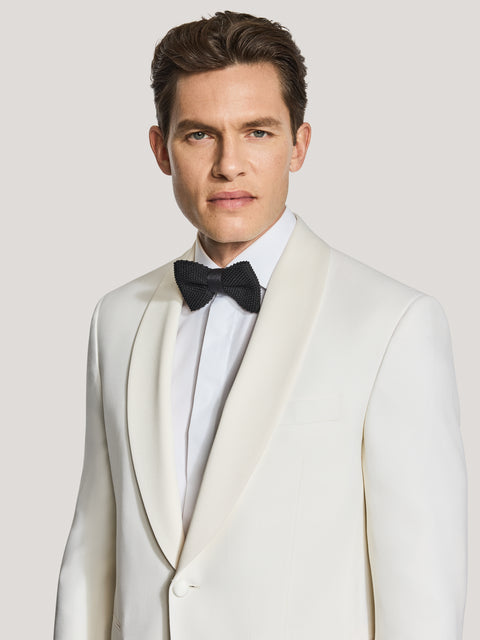 Cream dinner jacket with shawl collar worn with white dress shirt and black bow tie.