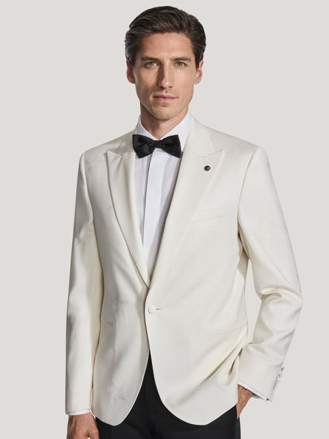 Cream-colored dinner jacket with notch lapels, single button, and star motif, worn with black bow tie and dress shirt.