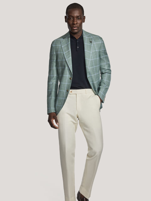 Sage green windowpane blazer worn with navy polo shirt, cream trousers, and dark shoes.