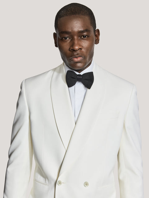 Cream double-breasted dinner jacket with peak lapels and satin trim, worn with white dress shirt and black bow tie.