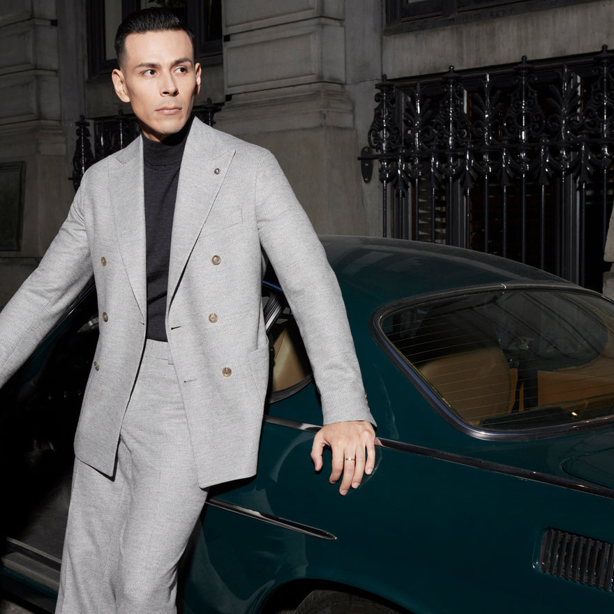 man standing next to classic car wearing a double breasted grey suit