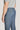 Medium blue trouser with plain front closure and button waistband, shown on model from side angle.