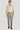 Man wearing sage green plain front trousers with a cream button-up shirt and dark loafers.