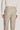 Sand-colored tailored trouser with side fastener closures and front pockets, paired with cream long-sleeve shirt.