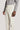 Cream corduroy tailored trouser with side tabs and buckle waistband detail, worn with gray sweater.