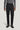 Charcoal wool tailored trousers with front pleats, side tabs, and belt loops on model wearing gray sweater.
