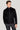 Black harrington jacket with spread collar and front zip closure worn with purple sweater and gray trousers.