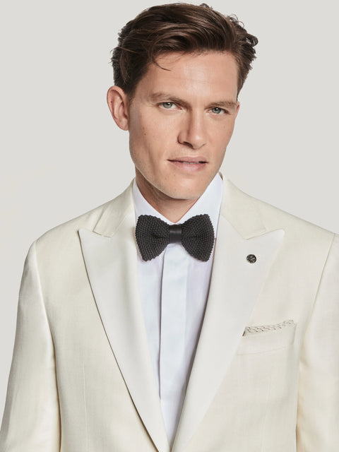 Cream herringbone dinner jacket worn with white dress shirt and black bow tie.