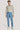 Man wearing light blue chino pants with patterned button-up shirt and white sneakers.