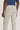 Light beige chino pants with flat front and button closure, shown from back view on male model wearing navy shirt.