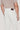 Off-white trouser with brown leather waistband label, five-pocket styling, worn with tan t-shirt.