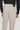 Light beige five-pocket trouser with brown leather waistband label, shown from back view on model wearing dark sweater.