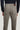 Taupe five-pocket trouser with brown leather waistband detail, shown from back view on model wearing navy top.