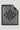 Gray throw blanket with black diamond monogram pattern, black border, and fringe trim on all edges.