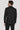 Man wearing black solid suit jacket and trousers, shown from back view.