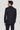 Man wearing navy solid stretch suit jacket and pants, shown from back view with light blue shirt collar visible.