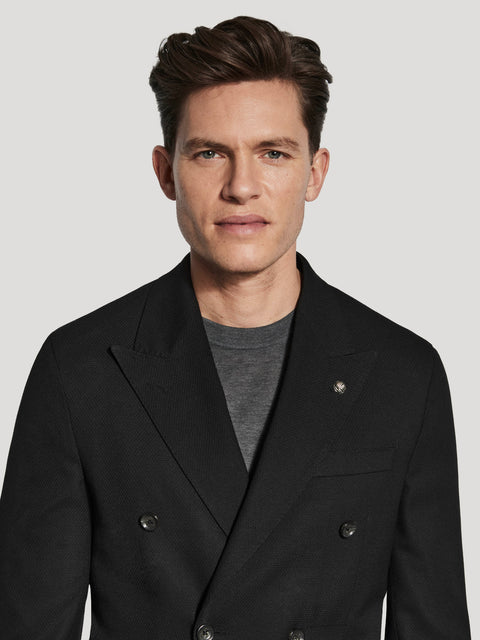 Black double-breasted knit blazer with textured fabric and button front, worn over gray t-shirt.