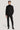 Black double-breasted tuxedo suit with peaked lapels, worn with black turtleneck and black dress shoes.