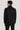Man wearing black double-breasted tuxedo jacket and trousers, shown from back view.