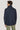 Man wearing navy field jacket with stand collar, shown from back view, paired with sage green trousers.