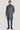 Man wearing a charcoal grey wool coat with button front and stand collar over blue jeans.