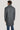 Man wearing grey wool coat over blue pants, shown from behind.