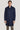 Dark blue wool coat with stand collar and three button front closure worn over white dress shirt.