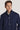 Dark blue wool coat with stand collar and button front closure worn by man over cream shirt.