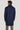 Man wearing dark blue wool coat with high collar, shown from back view with khaki trousers.