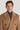 Camel wool coat with double-breasted button front, notched lapels, and chest pockets worn over charcoal turtleneck.