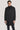 Charcoal wool coat with double-breasted button front and notch lapels worn over a navy turtleneck.