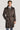Taupe double-breasted trench coat with notch collar, belt, and shoulder epaulettes worn over dress shirt and tie.