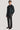 Man wearing dark charcoal shirt jacket with chest pockets and button front, paired with matching trousers and brown leather s