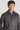 Man wearing grey herringbone shirt jacket with blue shirt underneath and dark buttons.