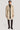 Sand-colored double breasted topcoat with brown buttons worn over black sweater and dark pants.