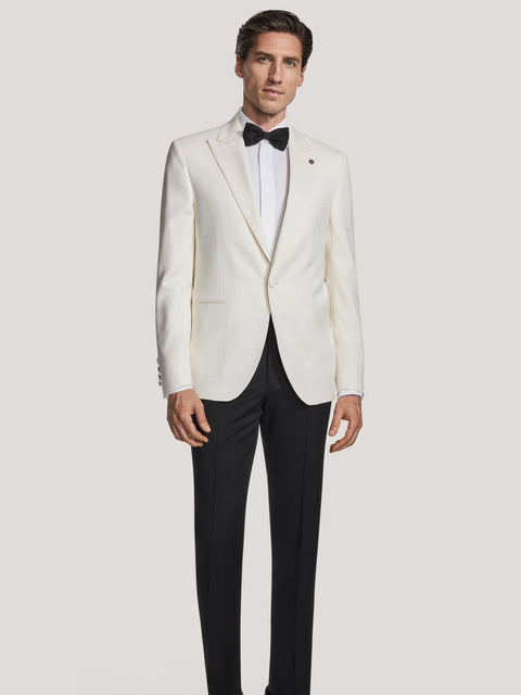 Man wearing cream dinner jacket with black bow tie, white dress shirt, and black trousers.