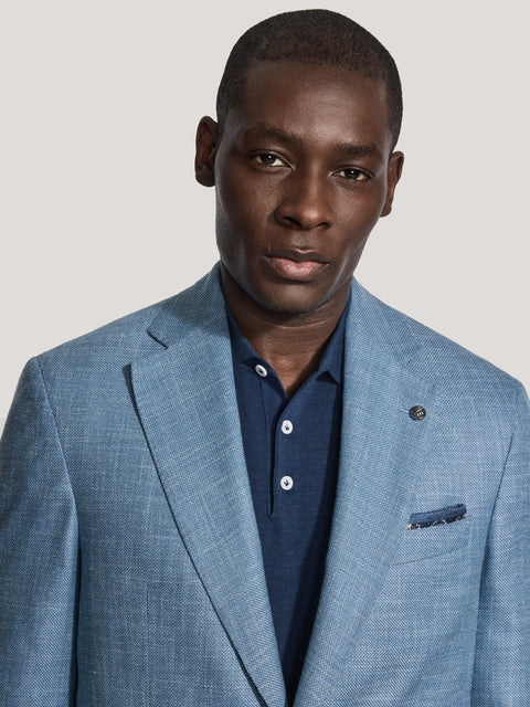 Light blue solid blazer with notch lapels, single button closure, and chest pocket detail worn over a navy shirt.