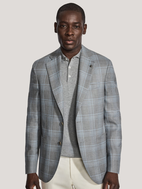 Grey plaid blazer with notch lapels and button closure, worn over a grey polo shirt and cream pants.