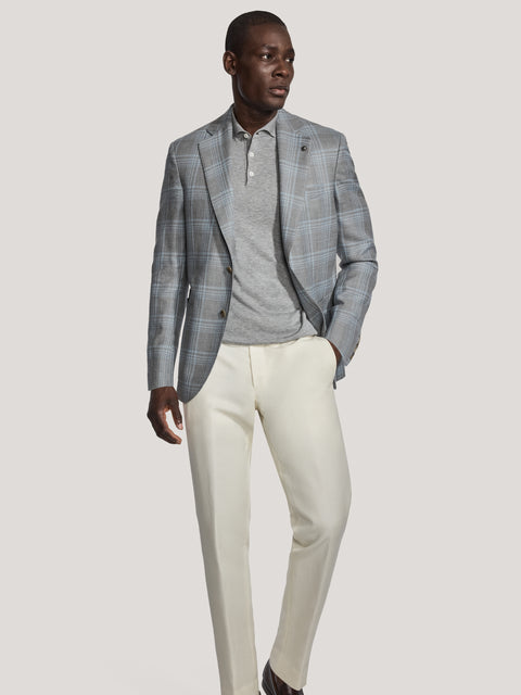 Grey plaid blazer with notch lapels worn over grey polo shirt and cream trousers.