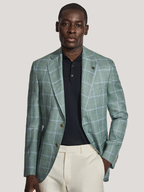 Sage green windowpane blazer with notched lapels, button front, worn over navy polo shirt and cream trousers.