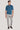 Man wearing teal short-sleeve polo shirt with white buttons and gray pants.