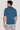 Man wearing teal short-sleeve polo shirt with ribbed collar and cuffs, shown from back.