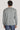 Man wearing grey cardigan with long sleeves over dark jeans, shown from back view.