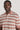 Man wearing a rose and cream striped polo shirt with short sleeves and button placket.