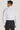 White dress shirt with long sleeves and collar, shown from back view on a model wearing black trousers.
