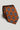Terracotta tie with repeating navy and cream geometric medallion pattern throughout.