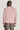 Pink crewneck sweatshirt with ribbed cuffs and hem, shown from back view on model wearing gray trousers.