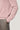 Pink crewneck sweatshirt with ribbed knit texture, shown with gray trousers.